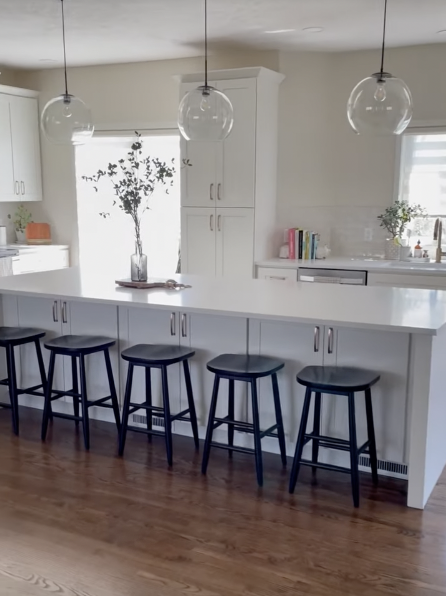 white kitchen with white island, cupboards, walls and 3 clear glass lights hanging over the island, remodeled by nastase contracting in omaha