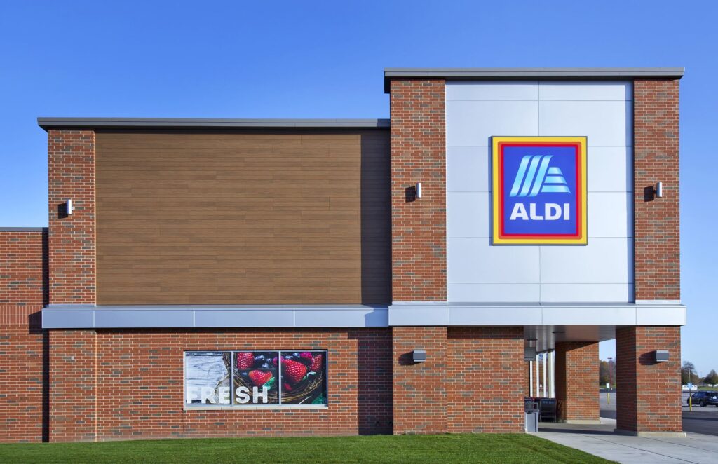 The photo showcases a commercial building with a modern architectural design, featuring what appears to be Nichiha siding. The siding has a wood-like finish that adds a warm, natural aesthetic to the structure. The building is a combination of this wood-like siding, red brick, and light gray panels, creating a visually appealing mix of textures and colors.